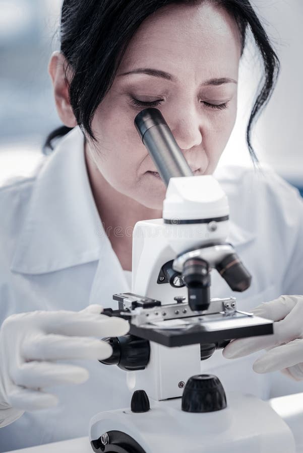 Fine su dello scienziato femminile che analizza lo scorrevole del microscopio immagine stock Fine su dello scienziato femminile che analizza lo scorrevole del microscopio immagine stock