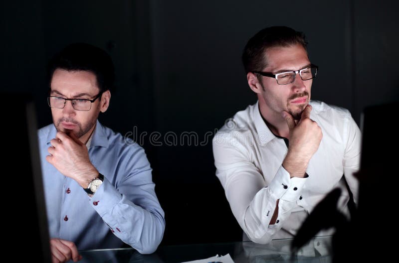 Fine in su due colleghi che lavorano tardi all'ufficio immagine stock libera da diritti Fine in su due colleghi che lavorano tardi all'ufficio immagine stock libera da diritti