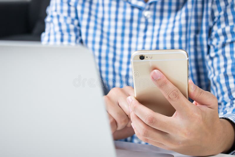 Fine in su L'uomo che indossa camice blu sta utilizzando i telefoni per acquisto online fotografia stock libera da diritti Fine in su L'uomo che indossa camice blu sta utilizzando i telefoni per acquisto online fotografia stock libera da diritti