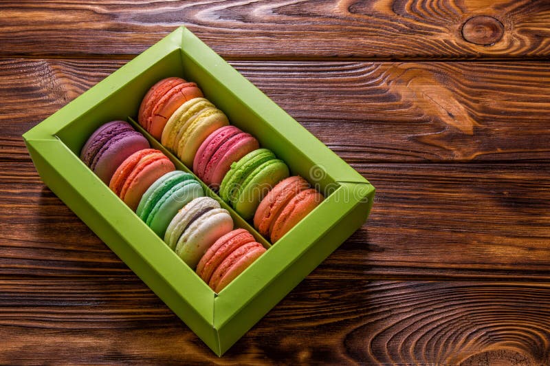 Fine in su Macarons francesi dolci e variopinti in una scatola verde chiaro su un fondo marrone di legno Copi lo spazio immagine stock Fine in su Macarons francesi dolci e variopinti in una scatola verde chiaro su un fondo marrone di legno Copi lo spazio immagine stock