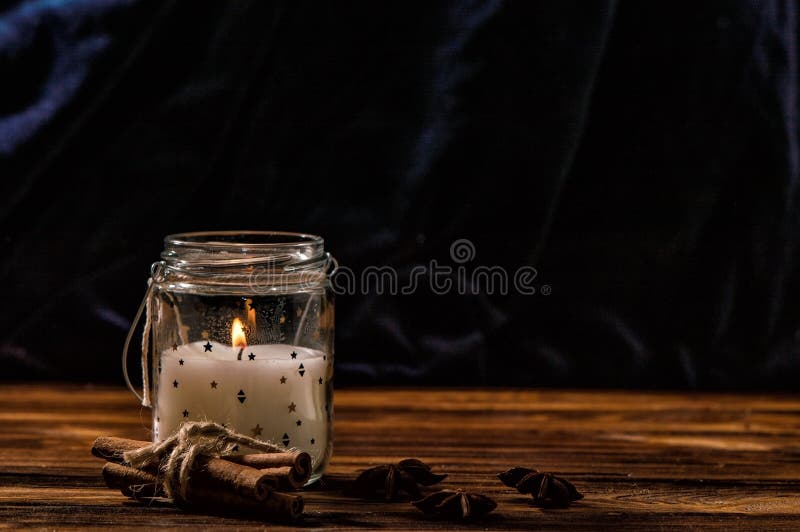 Fine in su Una candela bianca in un barattolo di vetro trasparente sta bruciando, cannella, anice è presentata intorno Tavola di immagine stock libera da diritti Fine in su Una candela bianca in un barattolo di vetro trasparente sta bruciando, cannella, anice è presentata intorno Tavola di immagine stock libera da diritti