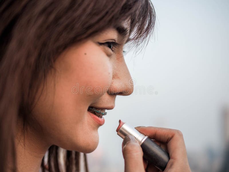Fine sulla bella donna asiatica che mette il rossetto di trucco, concetto felice della donna, cinematografico immagine stock libera da diritti Fine sulla bella donna asiatica che mette il rossetto di trucco, concetto felice della donna, cinematografico immagine stock libera da diritti