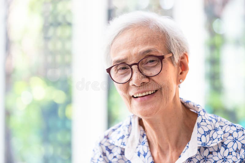 Fine sulla donna anziana asiatica in vetri che mostrano i denti diritti sani, sensibilità sorridente della donna senior del ritra fotografia stock libera da diritti