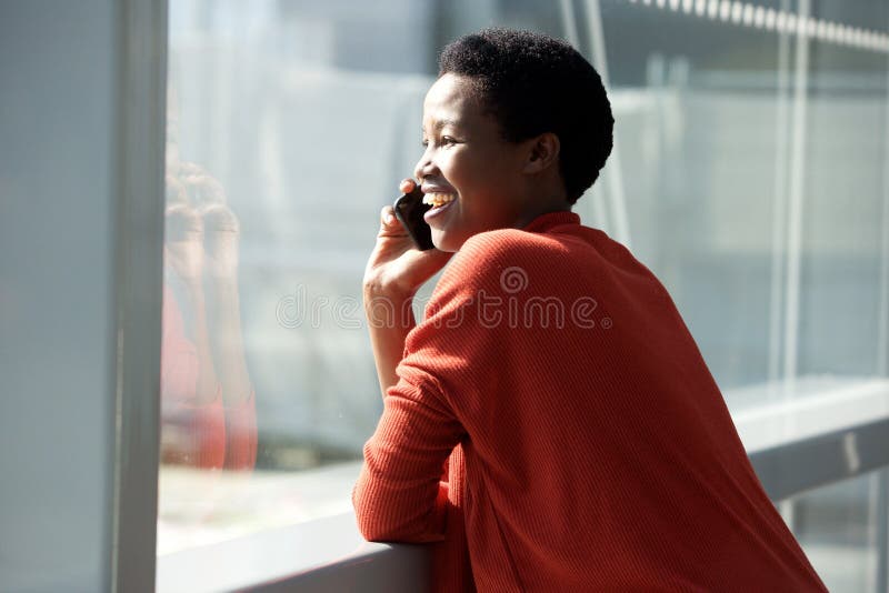 Fine sulla giovane donna felice che parla con il cellulare dalla finestra fotografie stock libere da diritti Fine sulla giovane donna felice che parla con il cellulare dalla finestra fotografie stock libere da diritti