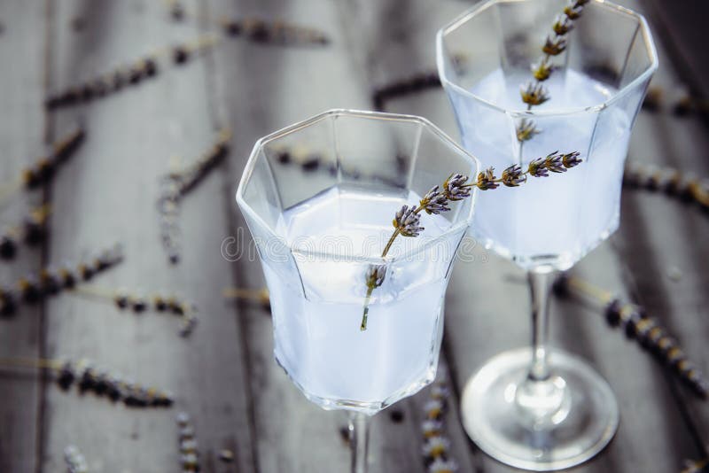 Fine sulla limonata fresca della lavanda con i fiori in bei vetri sulla tavola di legno scura alla luce posteriore Acqua della di fotografia stock Fine sulla limonata fresca della lavanda con i fiori in bei vetri sulla tavola di legno scura alla luce posteriore Acqua della di fotografia stock