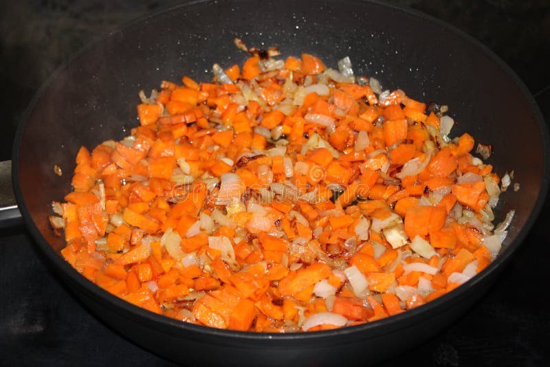 Finely Chopped Carrots and Onions are Fried in a Pan Stock Image