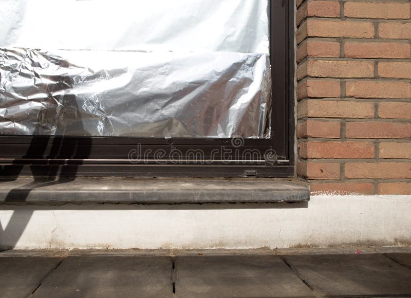 Finestra isolata con foglio di alluminio per proteggere casa dall'onda termica fotografia stock Finestra isolata con foglio di alluminio per proteggere casa dall'onda termica fotografia stock