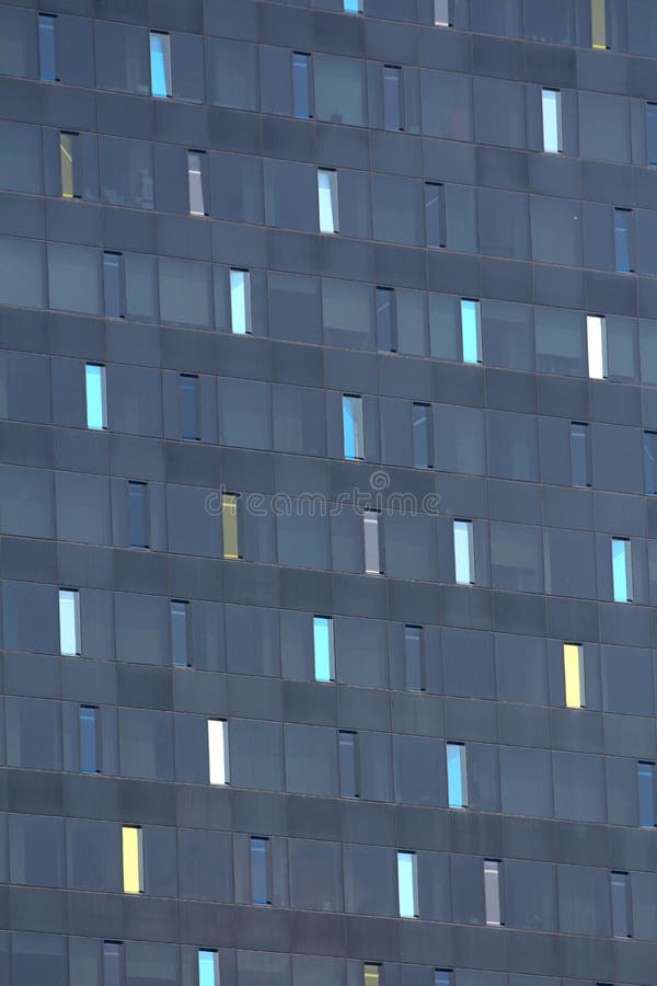 Finestre variopinte strette alte sul nuovo fondo moderno scuro di struttura dell'edificio per uffici fotografia stock Finestre variopinte strette alte sul nuovo fondo moderno scuro di struttura dell'edificio per uffici fotografia stock