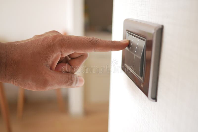 A finger turning on lighting switch. stock photos