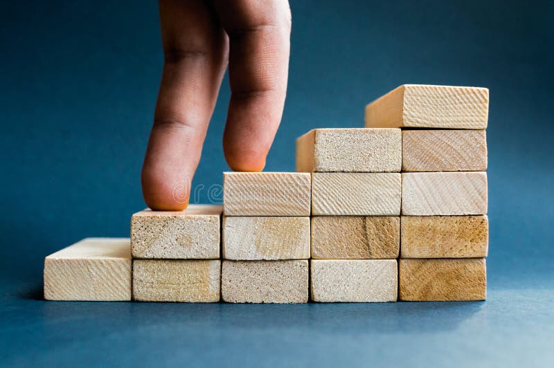 Fingeres que suben las escaleras hechas con los bloques de madera Concepto del éxito, carrera, logro de la meta, trabajador