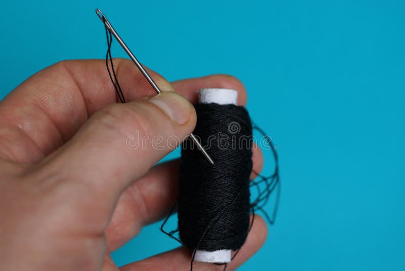 Fingers Holding a Needle with a Black Thread and a Coil on a Blue  Background Stock Image - Image of needle, linen: 120205223