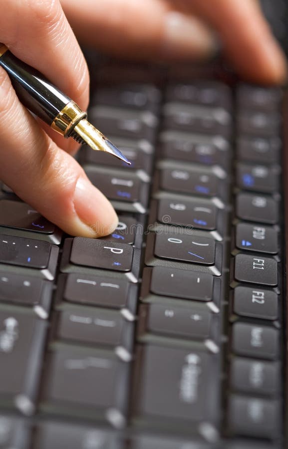 Fingers holding pen over keyboard