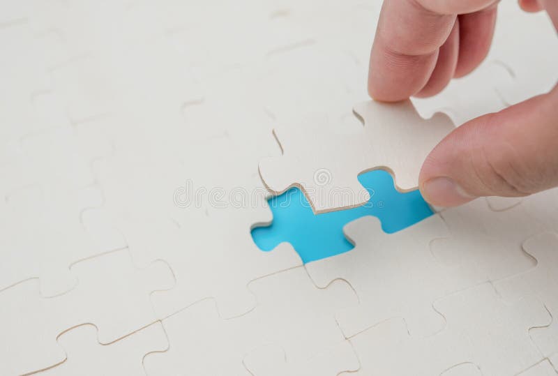 Finishing the last piece of jigsaw puzzle game on blue royalty free stock image Finishing the last piece of jigsaw puzzle game on blue royalty free stock image