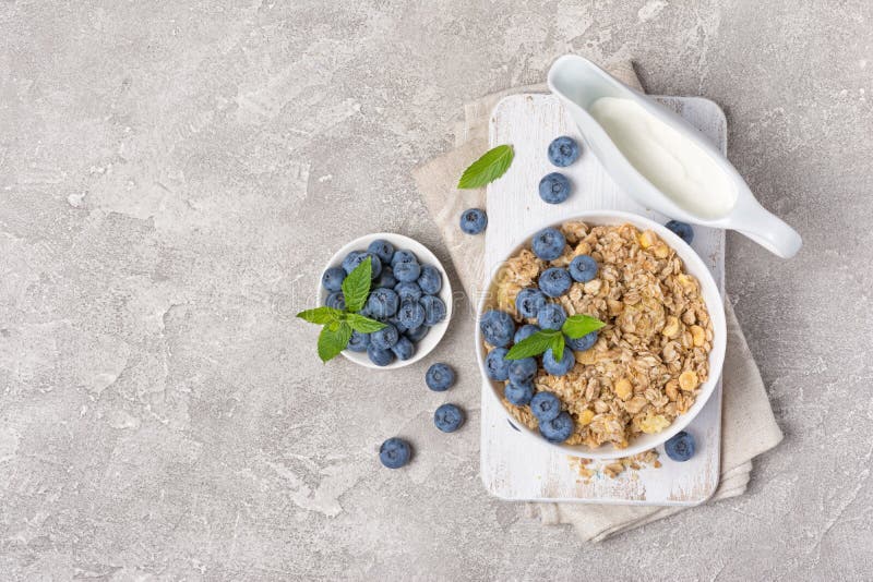 Fiocchi di avena o di granola con mirtilli freschi e latte per colazione sana fotografia stock libera da diritti Fiocchi di avena o di granola con mirtilli freschi e latte per colazione sana fotografia stock libera da diritti