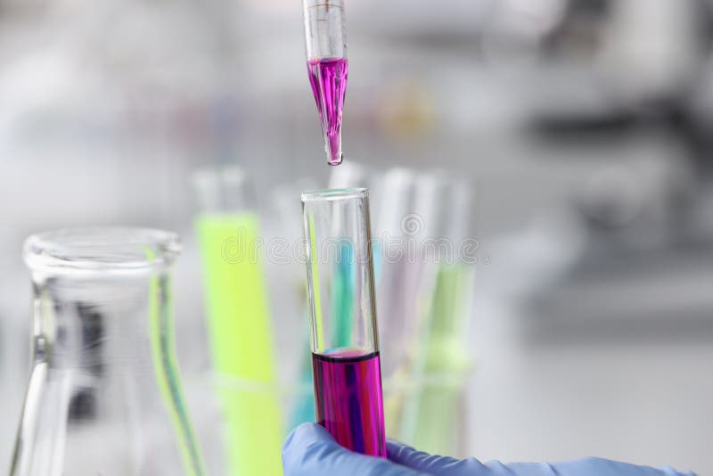 Purple liquid is dropped from pipette into test tube. Development of chemical compounds concept. Purple liquid is dropped from pipette into test tube. Development of chemical compounds concept