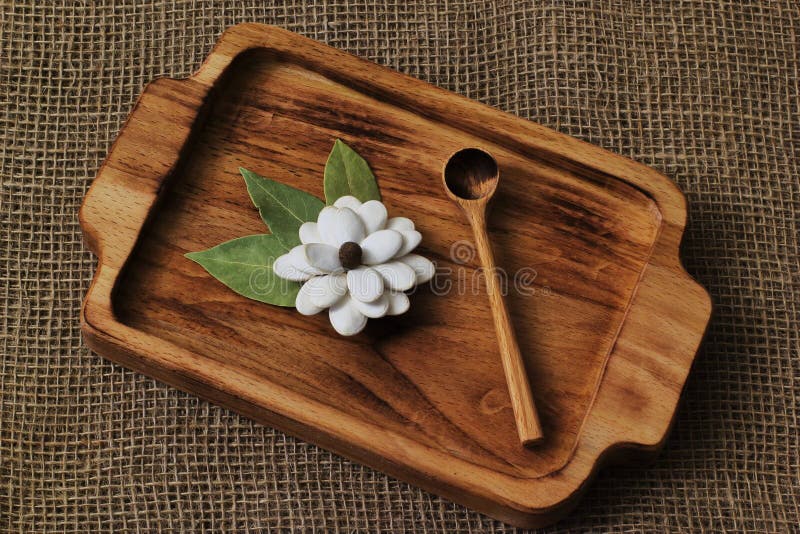 Fiore casalingo originale dai semi di zucca e dalle foglie della baia con il cucchiaio di legno sul vassoio del faggio su fondo h fotografia stock libera da diritti Fiore casalingo originale dai semi di zucca e dalle foglie della baia con il cucchiaio di legno sul vassoio del faggio su fondo h fotografia stock libera da diritti