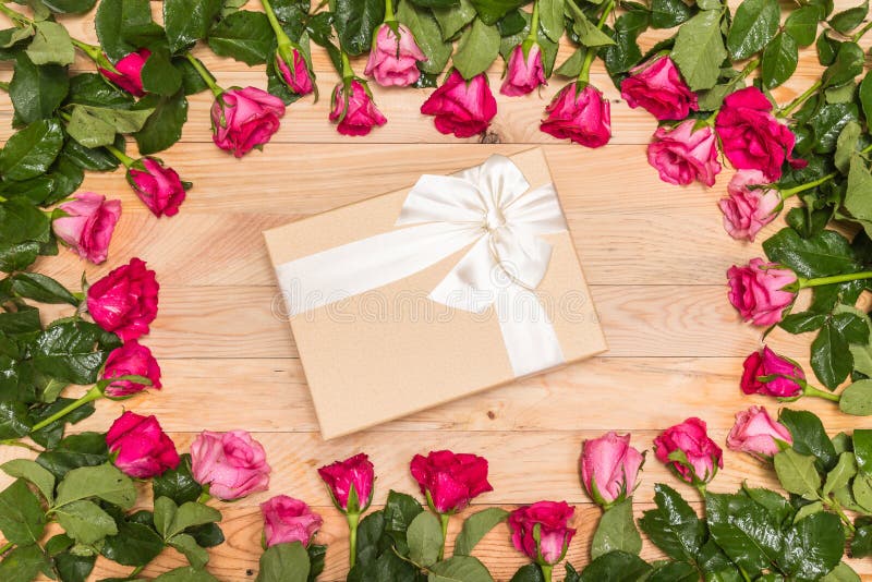 Top view fresh pink rose flower and gift box on wooden deck. For love or valentine day concept. Top view fresh pink rose flower and gift box on wooden deck. For love or valentine day concept