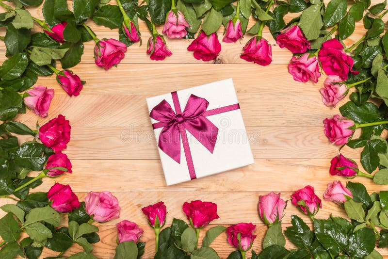 Top view fresh pink rose flower and gift box on wooden deck. For love or valentine day concept. Top view fresh pink rose flower and gift box on wooden deck. For love or valentine day concept