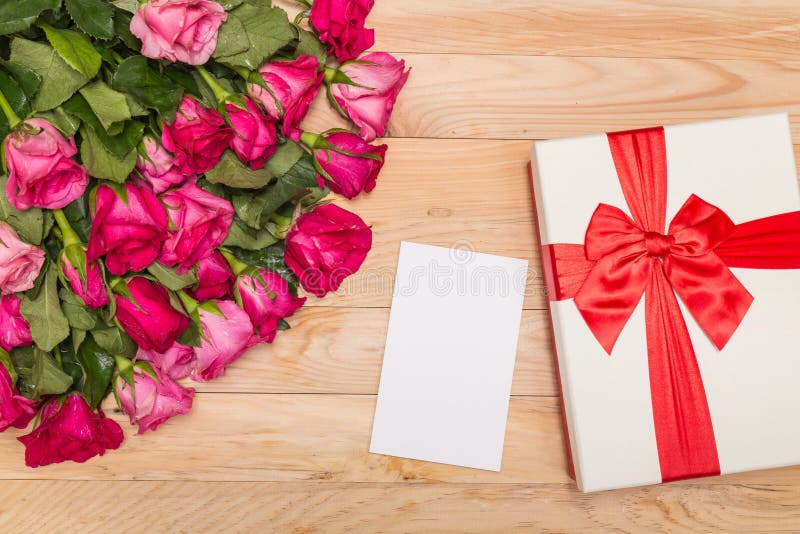 Top view fresh pink rose flower and gift box on wooden deck. For love or valentine day concept. Top view fresh pink rose flower and gift box on wooden deck. For love or valentine day concept