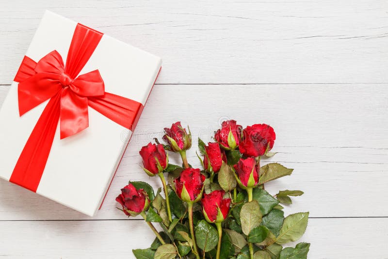 Top view fresh red rose flower and gift box on white wooden deck with empty space for design. For love or valentine day concept. Top view fresh red rose flower and gift box on white wooden deck with empty space for design. For love or valentine day concept