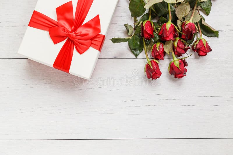 Top view fresh red rose flower and gift box on white wooden deck with empty space for design. For love or valentine day concept. Top view fresh red rose flower and gift box on white wooden deck with empty space for design. For love or valentine day concept