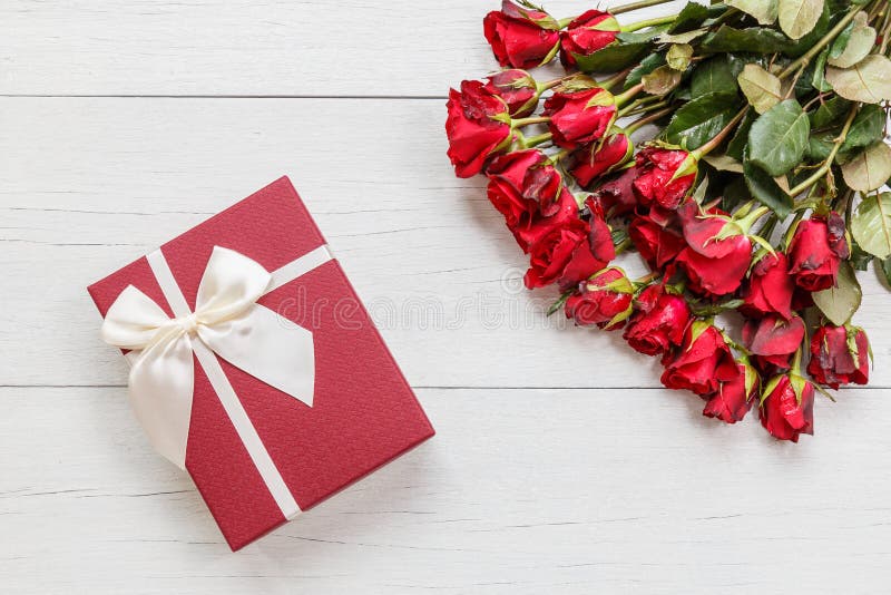 Top view fresh red rose flower and gift box on white wooden deck with empty space for design. For love or valentine day concept. Top view fresh red rose flower and gift box on white wooden deck with empty space for design. For love or valentine day concept