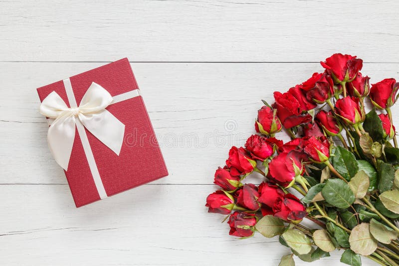 Top view fresh red rose flower and gift box on white wooden deck with empty space for design. For love or valentine day concept. Top view fresh red rose flower and gift box on white wooden deck with empty space for design. For love or valentine day concept