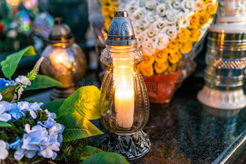 Fiori artificiali e reali e candele accese che si trovano sulla pietra tombale nel cimitero fotografia stock Fiori artificiali e reali e candele accese che si trovano sulla pietra tombale nel cimitero fotografia stock