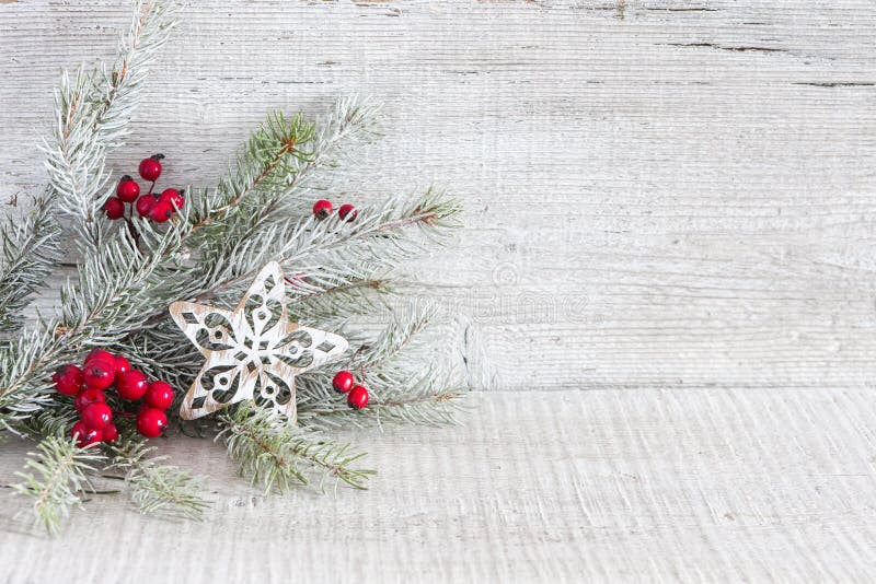 Fir branch with Christmas decorations on white rustic wooden background.