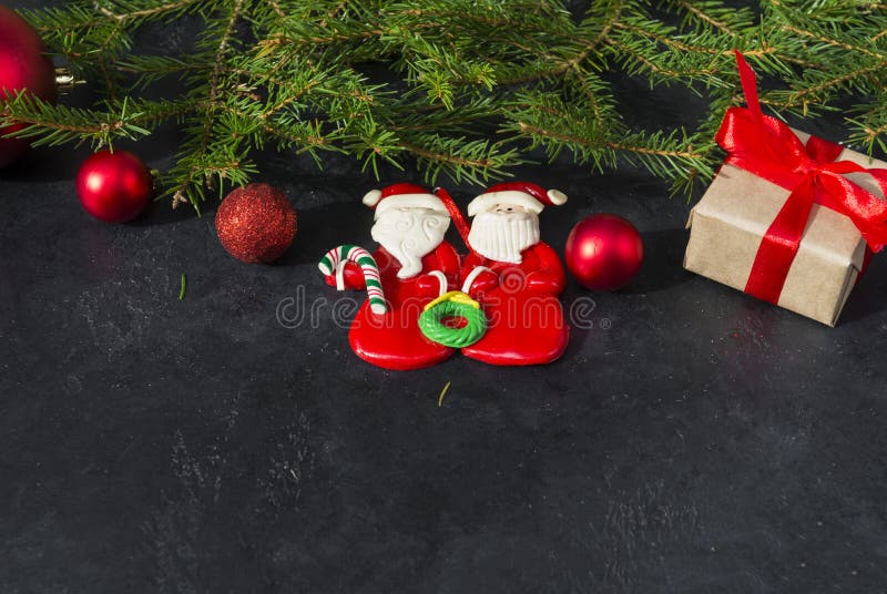 Fir branches, 2 toy Santa Claus, gift box tied with red ribbon, red balls on black background, Christmas stock photography Fir branches, 2 toy Santa Claus, gift box tied with red ribbon, red balls on black background, Christmas stock photography