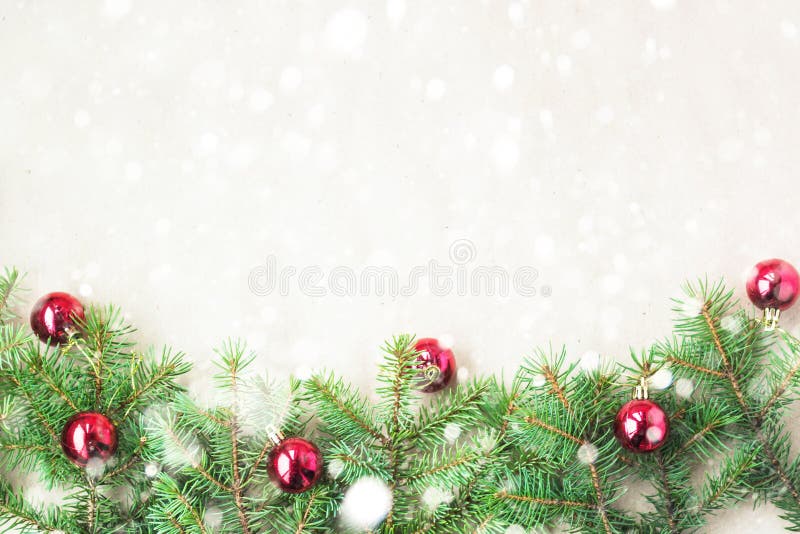 Fir tree branches decorated with red christmas balls as border on a rustic holiday background frame with snow copy space