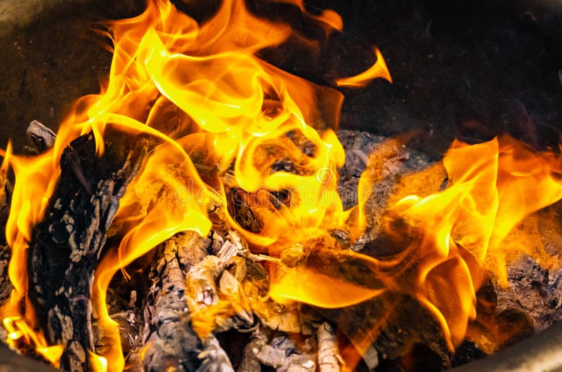 Fire burns in an iron basin. burning wood background