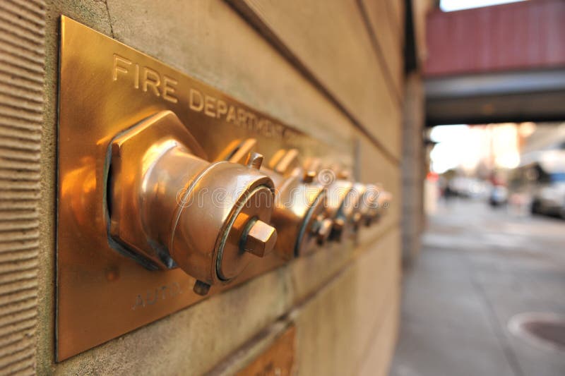 A set of fire hose conections on the wall of a building. A set of fire hose conections on the wall of a building