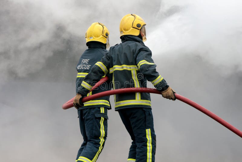 Fire fighters fighting fire with hose