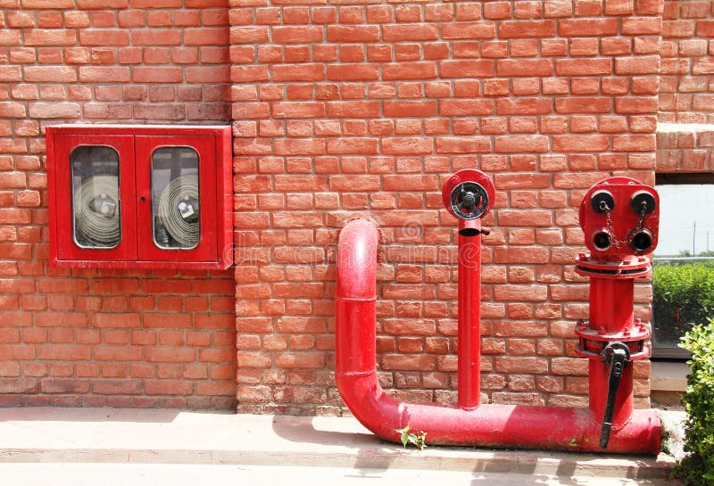 Fire hydrant,hose and pipes inserted on brick wall stock photo