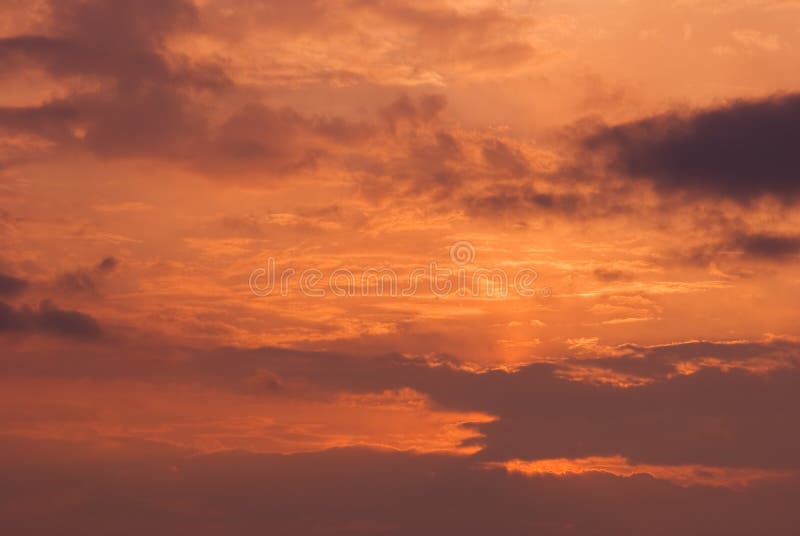 Fire sky background. Soft clouds with the hint of the sun at sunset. Many orange tones and patterns of clouds