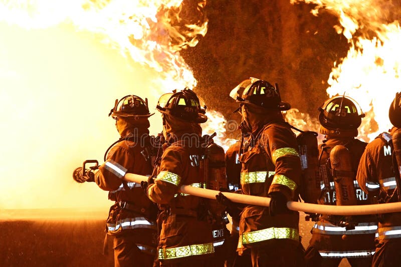 De cerca de heroico bomberos en negocios El gran mangueras sobre el batalla revoloteando llamas de incendio objeto.