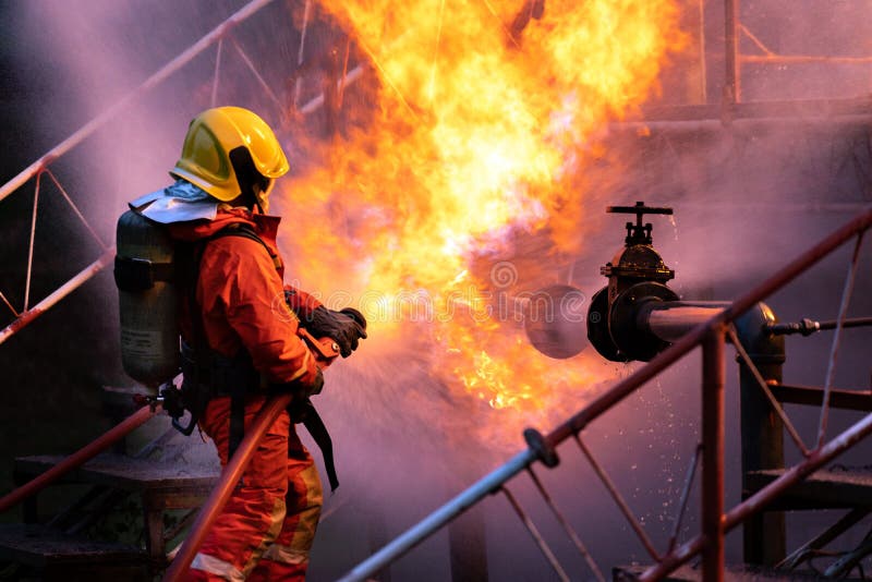 Firefighters using water fog spraying down fire from oil rig factory explosion