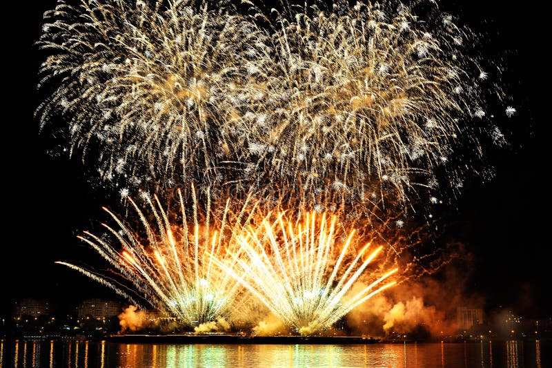 Firework over city at night with reflection in water