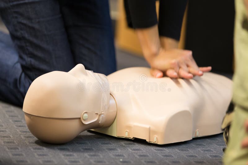 Un gruppo di studenti l'educazione degli adulti practitcing CPR petto compressioon su manichino.