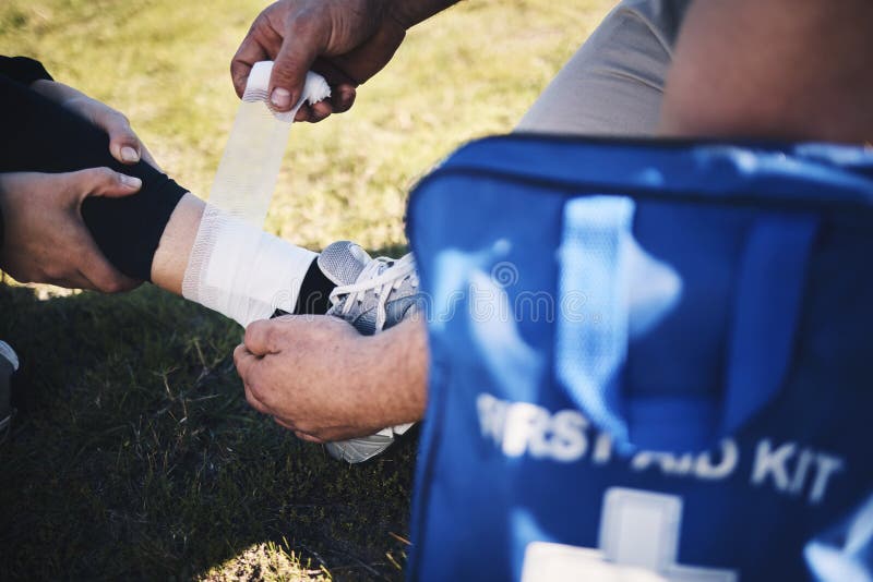 First aid, hands and man medic with ankle sports injury at field for running, training or marathon practice. Medical