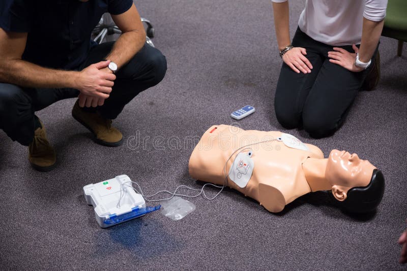 CPR training medical procedure workshop. Demonstrating chest compressions and use of AED automatic defibrillator on CPR doll. CPR training medical procedure workshop. Demonstrating chest compressions and use of AED automatic defibrillator on CPR doll.