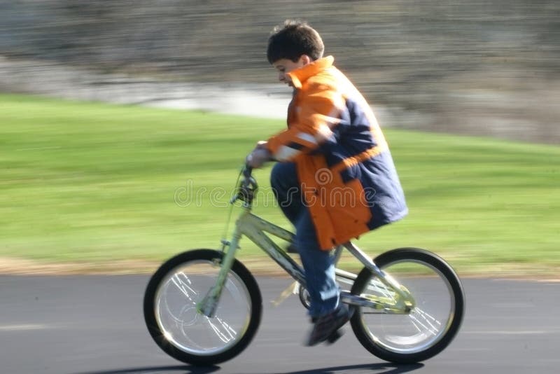 Giovane ragazzo sempre esercitare come egli impara a guidare una moto, catturati in movimento, su una strada privata.