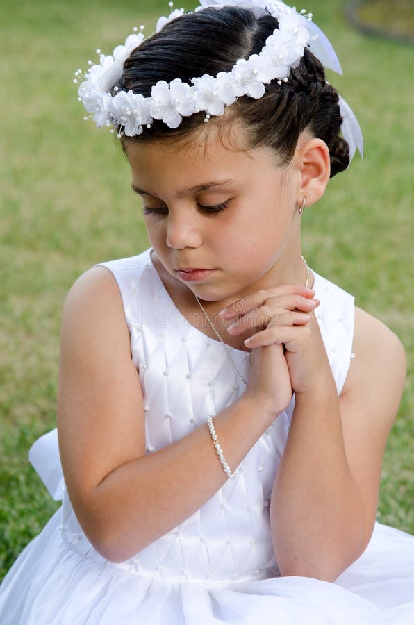 A little girl praying and looking down on the day of her first communion.