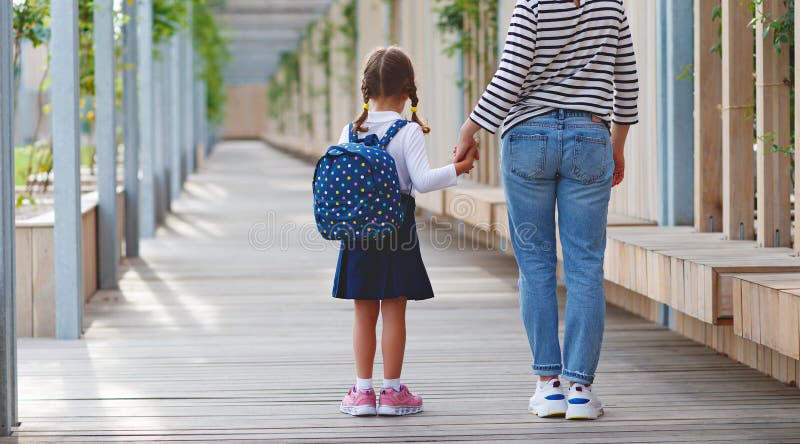 First day at school. mother leads little child school girl in f