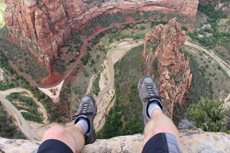 First person perspective shot from a hiker sitting at the edge of a cliff at Angel`s Landing in Zion National Park. First person perspective shot from a hiker sitting at the edge of a cliff at Angel`s Landing in Zion National Park.