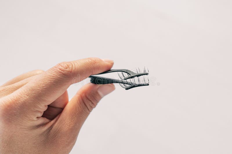 First person view of woman applying false magnetic eyelashes with metal applicator. Person holding pince to apply magnet fake royalty free stock photography First person view of woman applying false magnetic eyelashes with metal applicator. Person holding pince to apply magnet fake royalty free stock photography