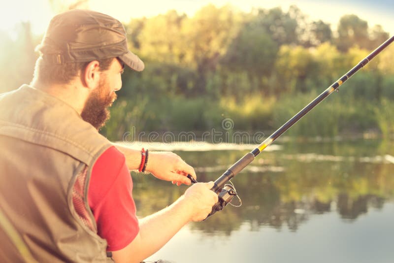 Fischen des jungen Mannes auf einem Fluss lizenzfreie stockfotografie Fischen des jungen Mannes auf einem Fluss lizenzfreie stockfotografie