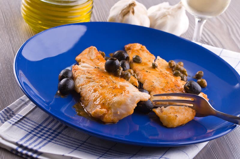 Fish fillet with black olives and capers. royalty free stock image