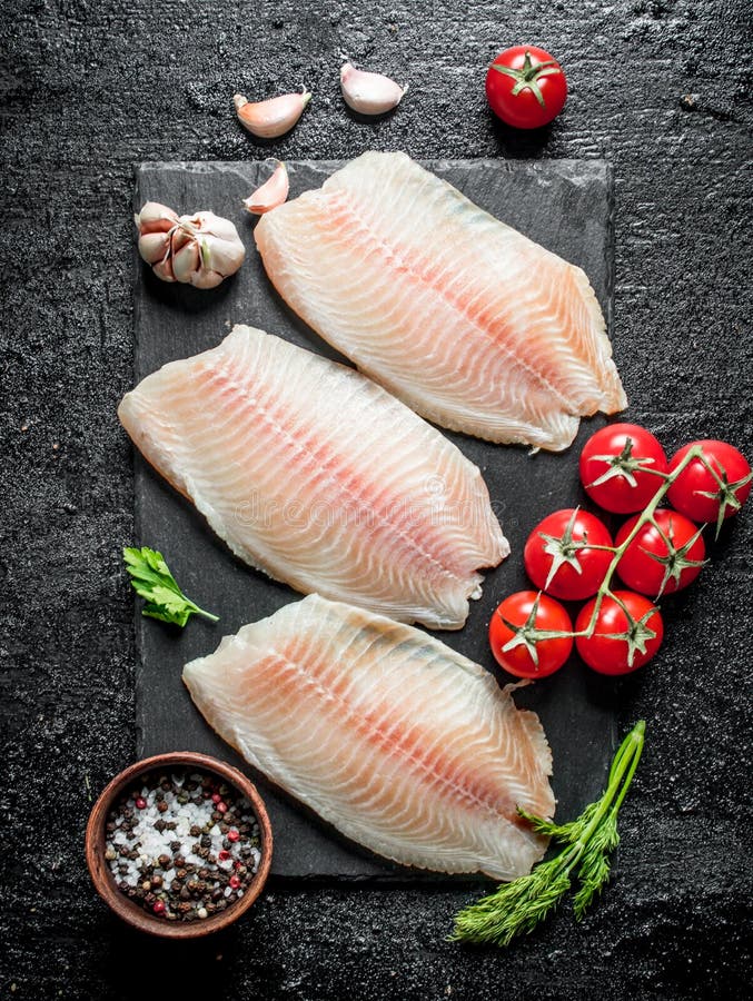 Fish Fillet on Black Stone Board with Dill, Tomatoes and Spices in Bowl